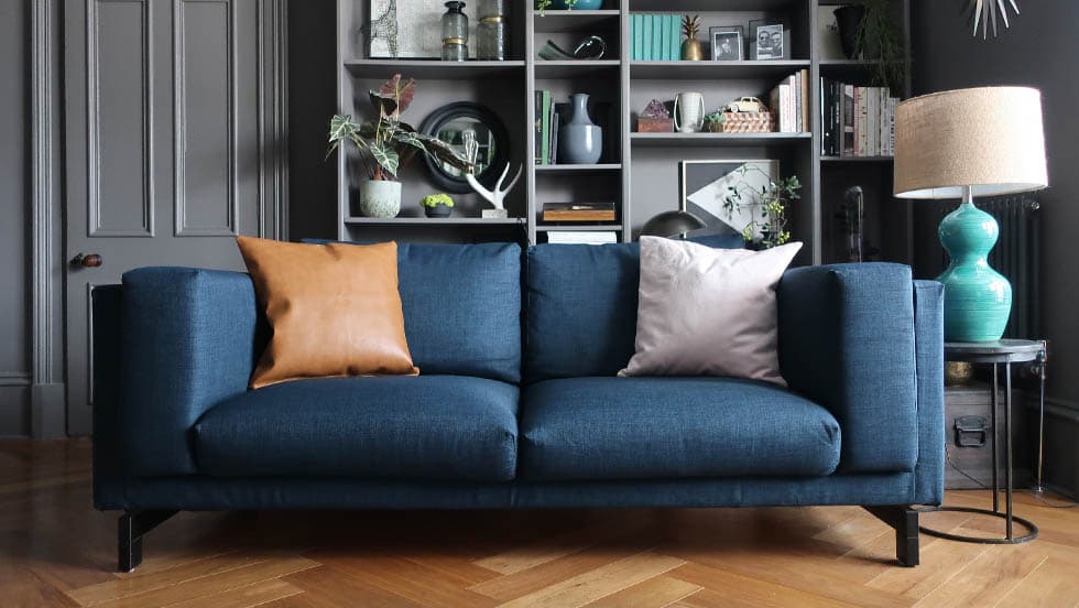 A navy blue IKEA Nockeby sofa in an industrial living room