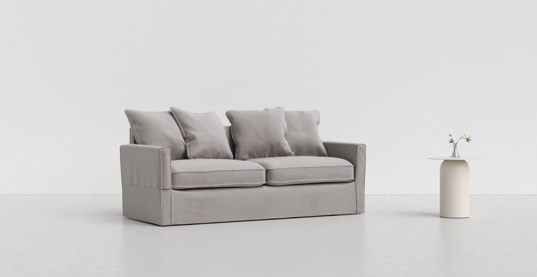 A medium grey Harnosand sofa on a lighter grey background with a white vase beside it