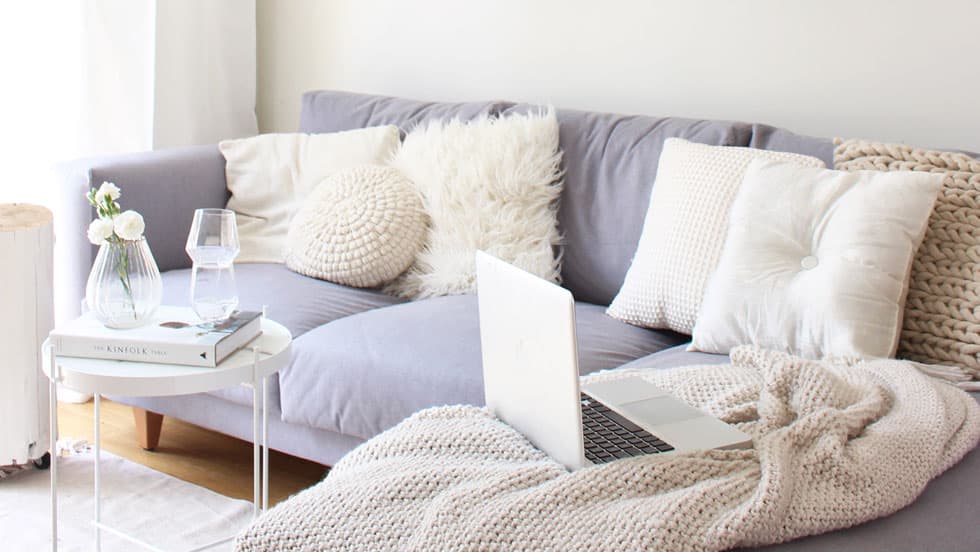 A pearl grey Norsborg sofa covered in white blankets and cushions