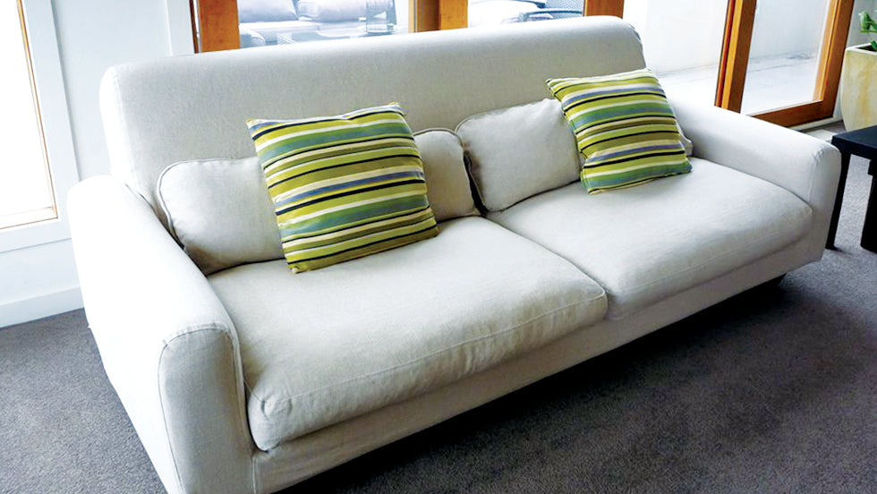 A cream IKEA Nikkala sofa with green striped cushions
