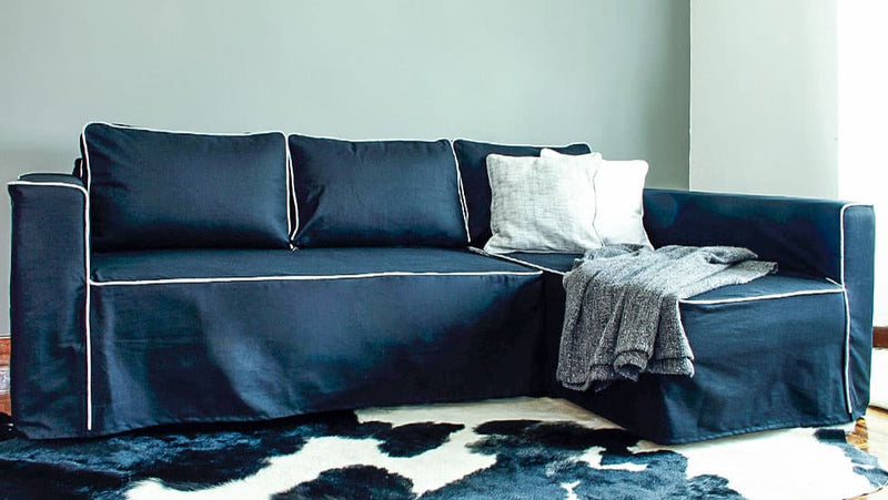 A navy blue IKEA Manstad sofa with white piping around the edges