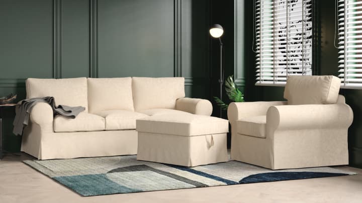 A collection of IKEA Ektorp sofa, armchair and foostool in cream long-skirt covers, in a bottle green living room