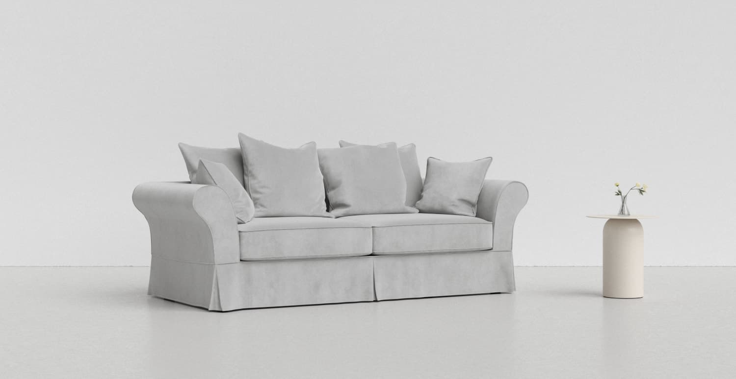 A light grey IKEA Backamo sofa on a lighter grey background with a white vase beside it