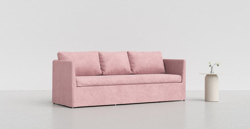  A rose pink Brathult sofa on a light grey background with a white vase beside it