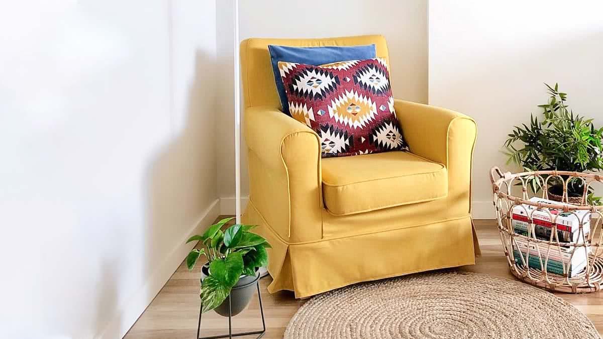 A bohemian-looking living room with an IKEA Ektorp Jennylund armchair in a yellow cover with a patterned cushion on it