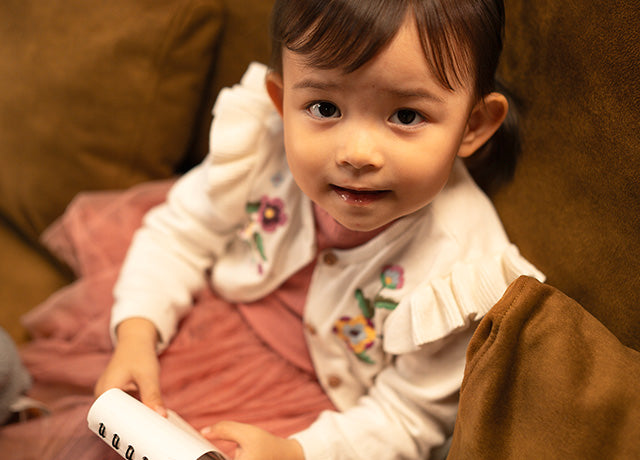 Close-up of a kid sitting on IKEA FARLOV three-seater sofa couch with Signature Velvet Caramel slipcover