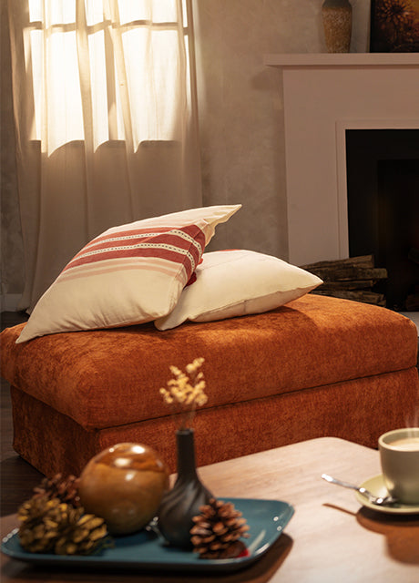 Cosy living space featuring a burnt orange ottoman with Comfort Works slipcover