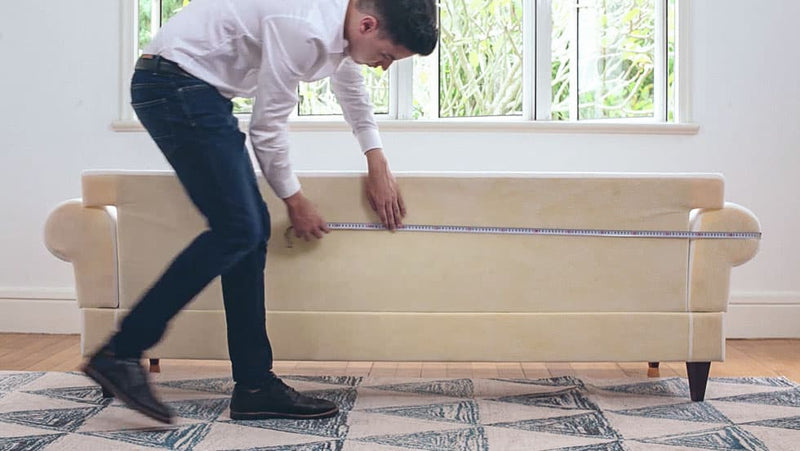 Man measuring the back of the IKEA EKTORP three seater sofa with measurement tape