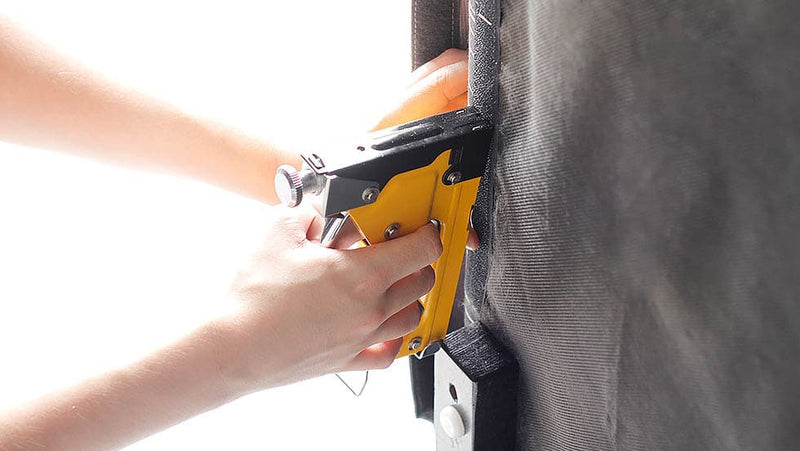 Hand stapling Velcro straps onto sofa 
