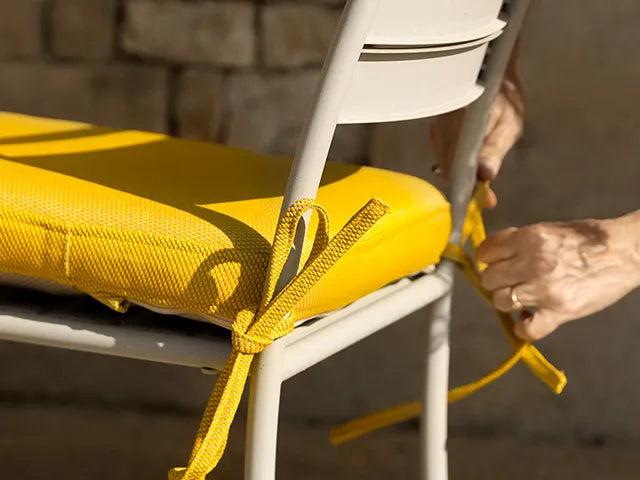 Hands-tying-seat-cushion-to-outdoor-chair-ComfortWorks-Care+Tweed-couch-cover-in-Amber