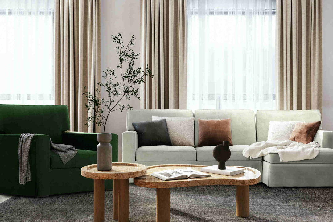 Modern living room with Crate and Barrel Axis II sofa in Performance Weave Stone and Classic Velvet Forest Green slipcover