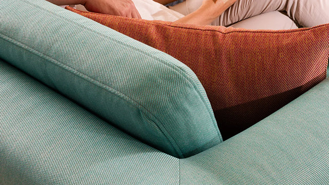 Closeup of a sofa corner ComfortWorks Care+Tweed couch cover in mineral blue and sunset color
