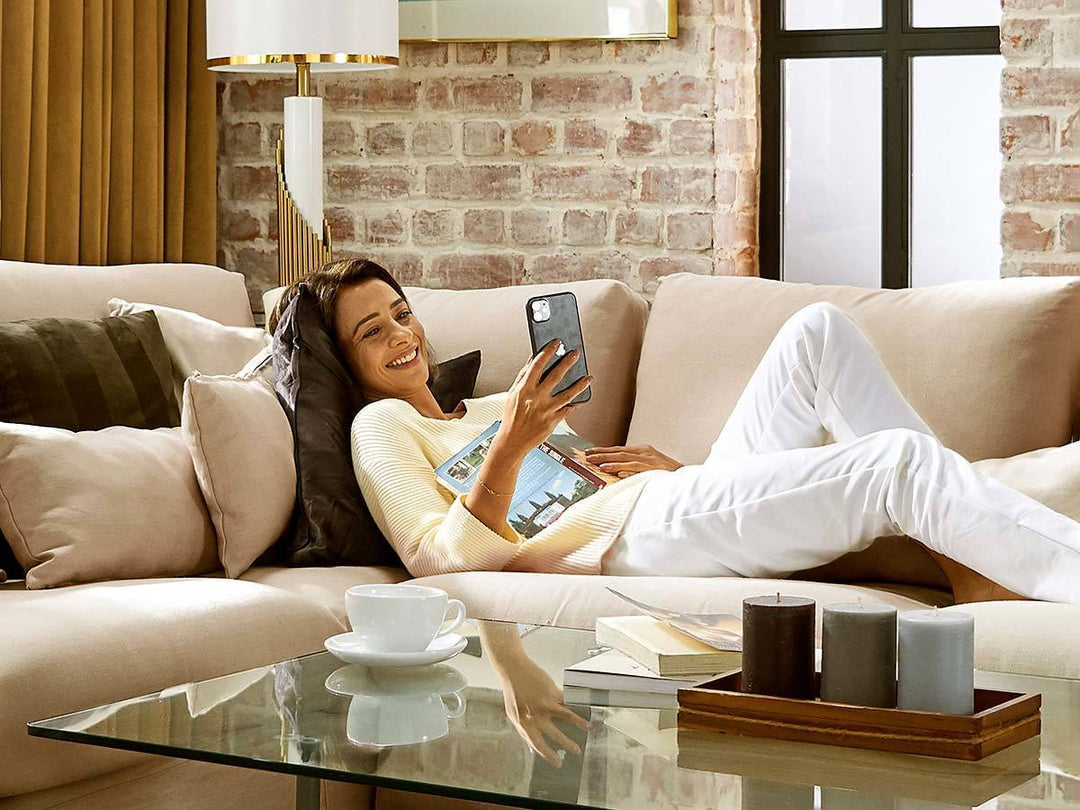 Close-up of a woman reading a book on a sofa with white Pure Linen slipcover in a Scandinavian living room