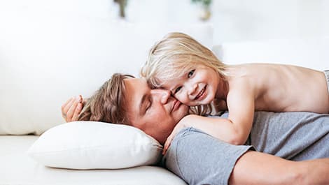 Father resting on a white Cotton Canvas slipcovered cushion with child cuddling on top