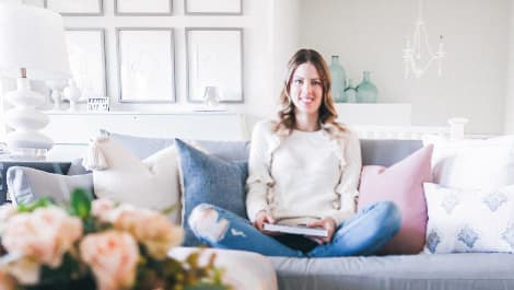 Woman sitting on a sofa with cushions while reading a book