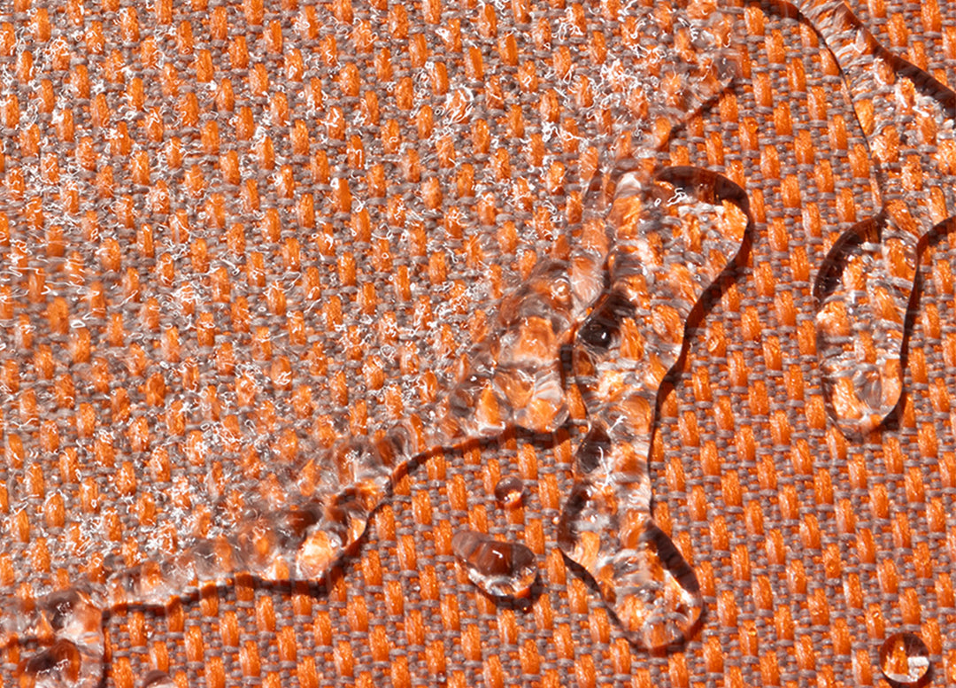 Close-up of water-resistant Performance Tweed Tangerine fabric with beads of water on it