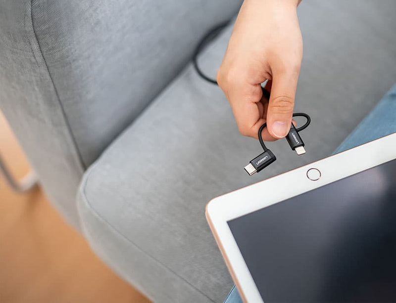 Woman trying to connect the USB cable from the smart sofa slipcover to the tablet (Alternate angle)