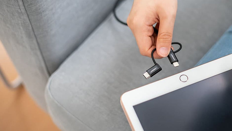Woman trying to connect the USB cable from the smart sofa slipcover to the tablet