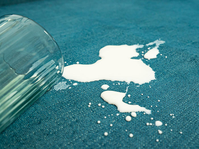Close-up of spilled milk on a sofa with spill-resistant Teal Performance Weave slipcover