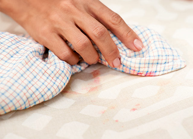 Hand-wiping-off-drink-spills-on-ComfortWorks-performance-fabric-Sunbrella-Fretwork-liquid-repellent-coating-and-spill-resistant-sofa-chair-cover