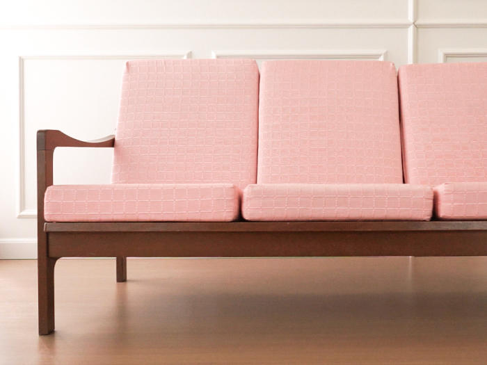 Close-up of three-seater sofa couch cushion with pink slipcover